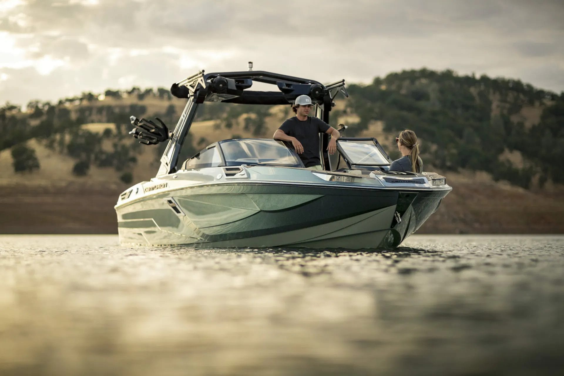 A couple is sitting on a wakesurf boat.