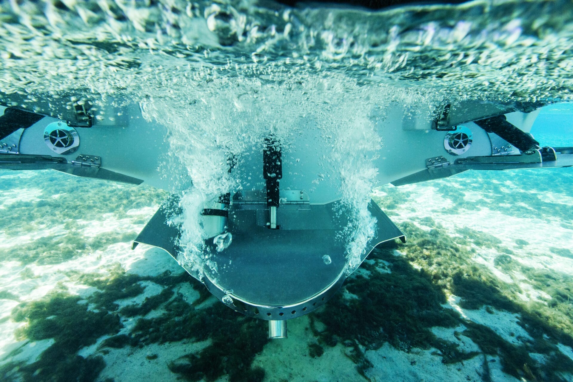 Underwater view of a submersible or aquatic vehicle with propulsion system activated, creating bubbles and turbulence in clear water over a sandy, algae-covered seabed. Imagine how you could customize your ride to explore the depths with personalized flair and advanced technology.