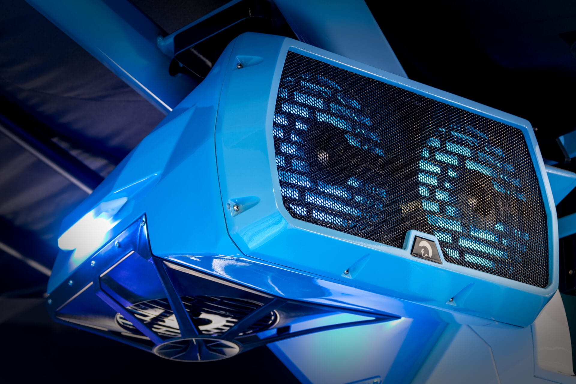 Close-up of a blue industrial fan system with two visible fans behind a mesh grille, seamlessly integrated to create the perfect atmosphere, as if you've chosen to Customize My Ride for your cooling needs, all elegantly mounted on the ceiling.