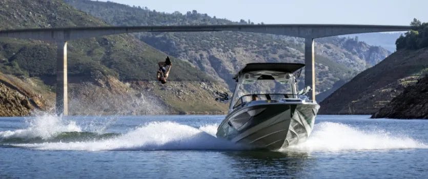 A man is jumping off a wakesurf boat into the water.