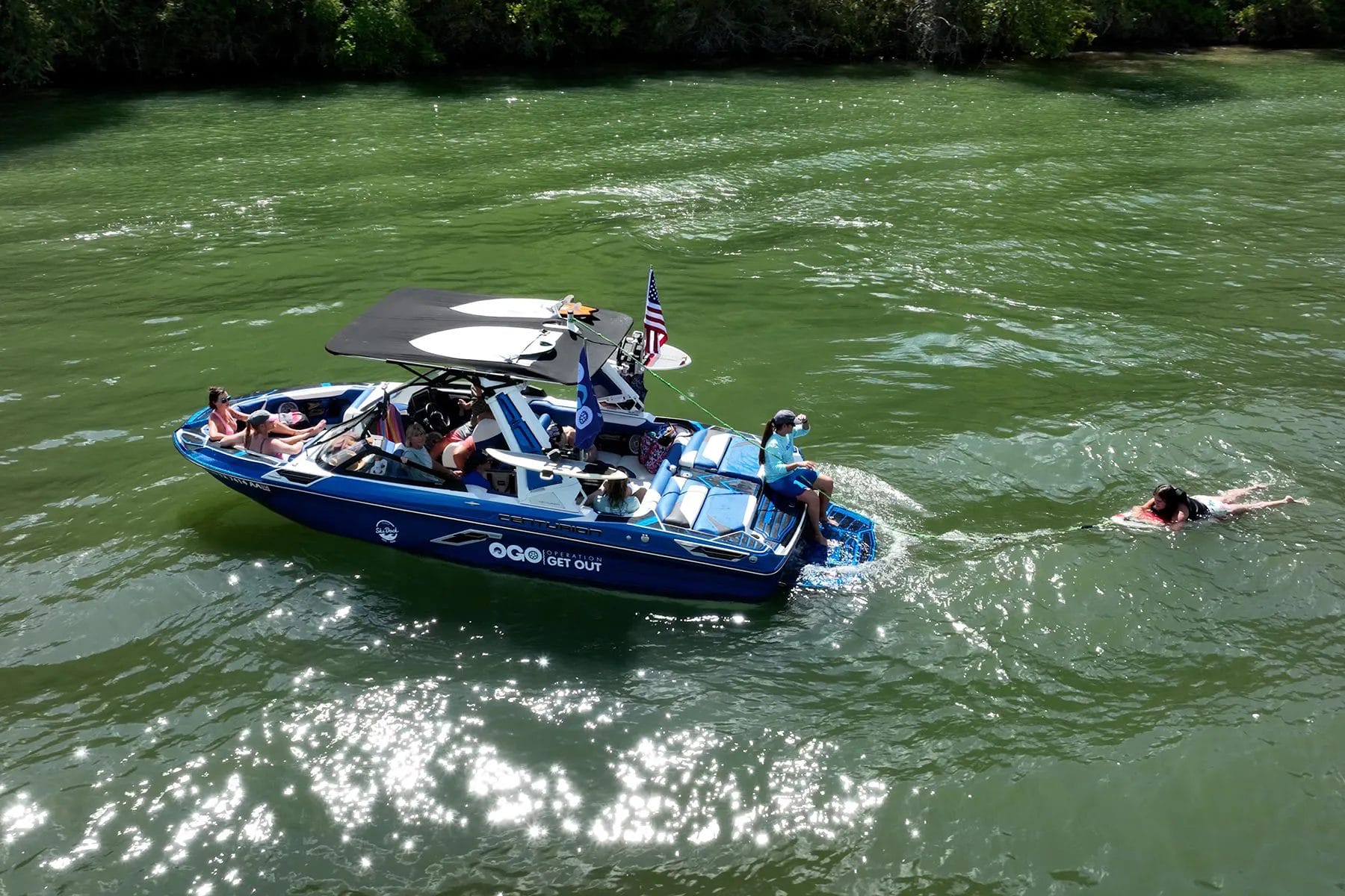 A group of people are wakesurfing on a boat.