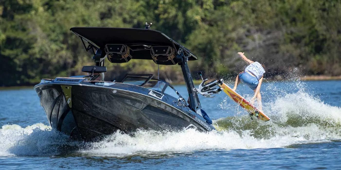 A man riding a wakeboard on a wakesurf boat.