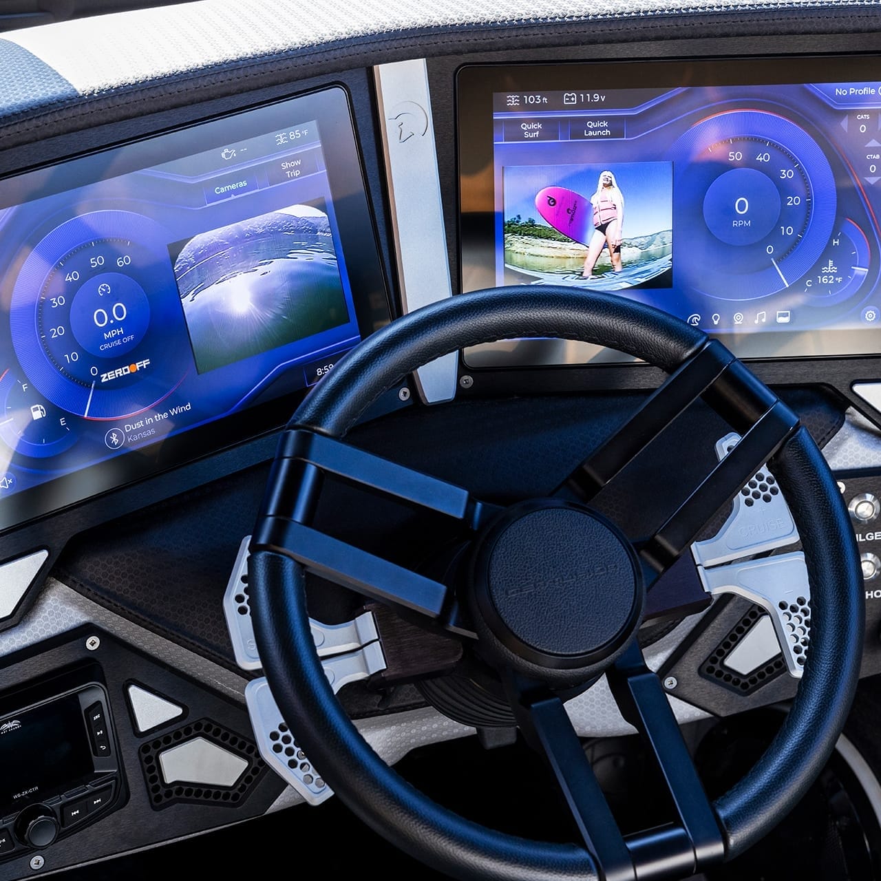 Close-up of the Centurion Ri230 boat dashboard, featuring two touchscreen displays for speed and navigation, alongside a sleek black steering wheel.