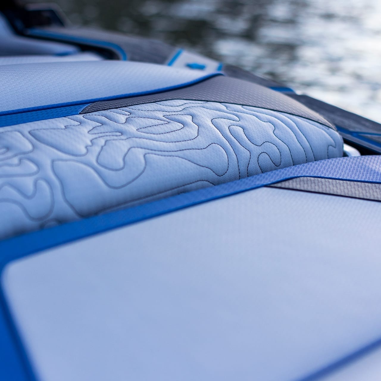 Close-up of a textured blue and white seat with a wavy pattern, aboard the Centurion Ri230, positioned gracefully by the water.