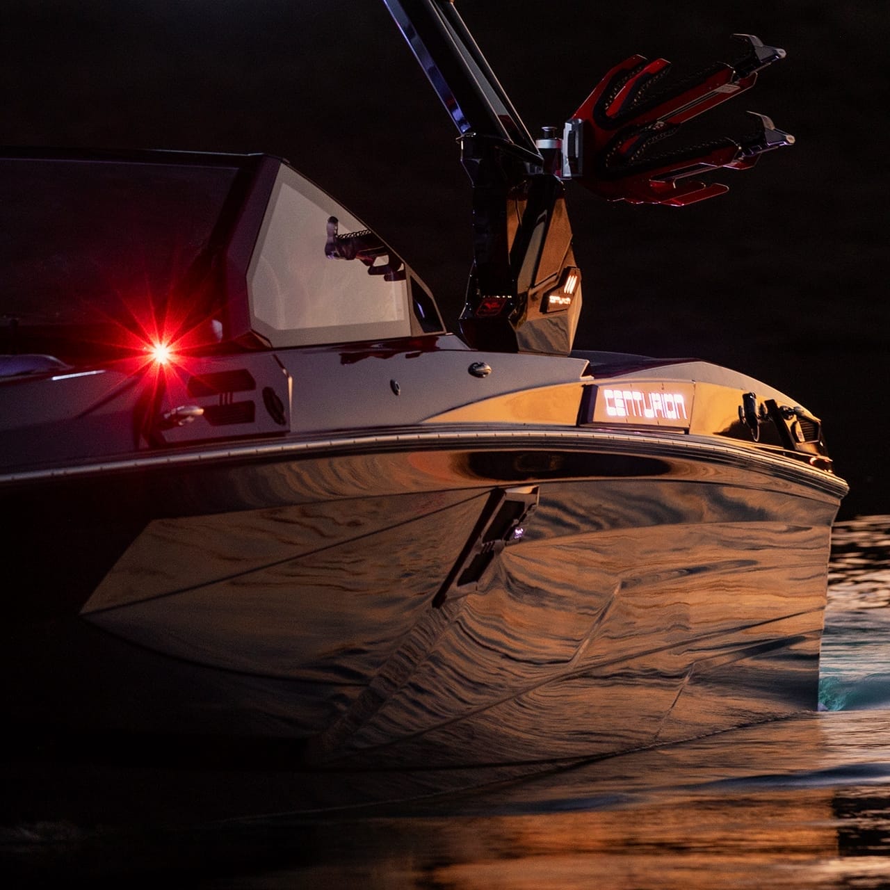 A sleek black Centurion Ri265, illuminated by red and white lights, is captured in low-light conditions, cutting through the water's surface.