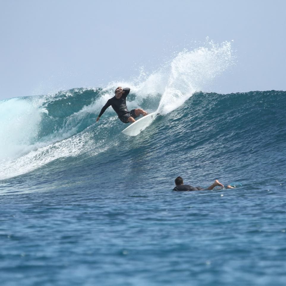 A surfer riding a wave on a wakesurf board.