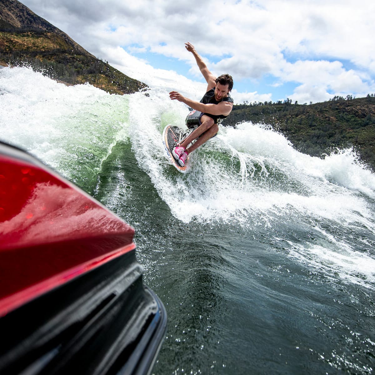 A man riding a wave on a wakesurf board.