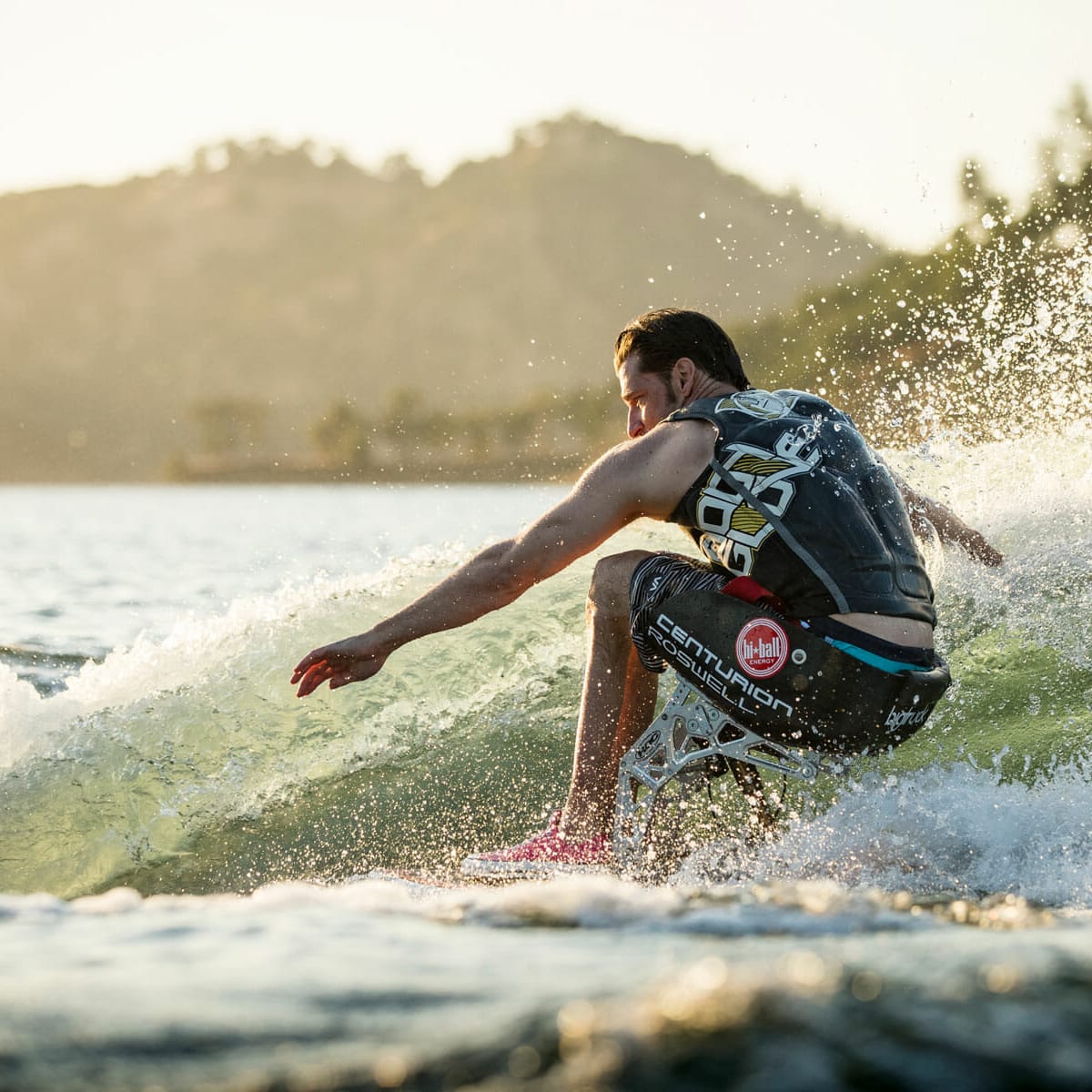 A man riding a wave on a wakesurf board.