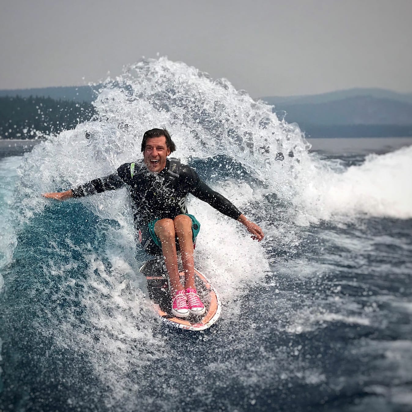 A person riding a wave on a wakesurf board.