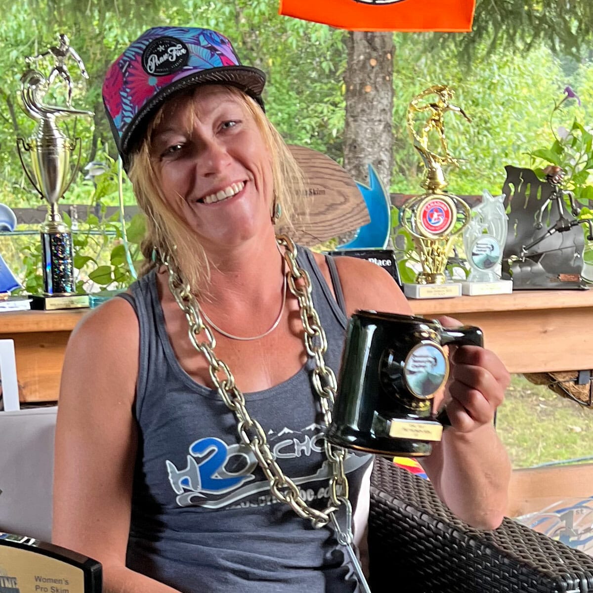 A woman holding a cup of coffee and trophies.