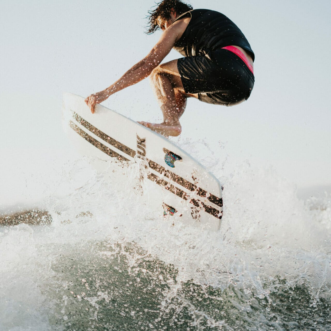 A man wakesurfing behind a boat on a wave.