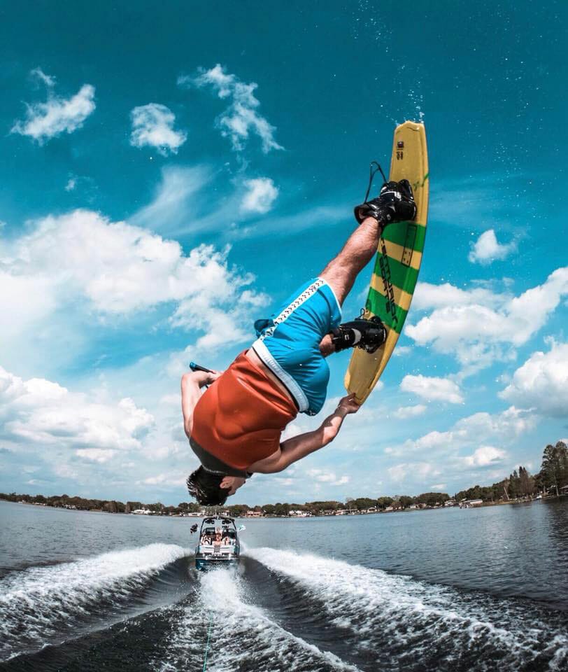 A man performing a trick on a wakesurf board behind a boat.