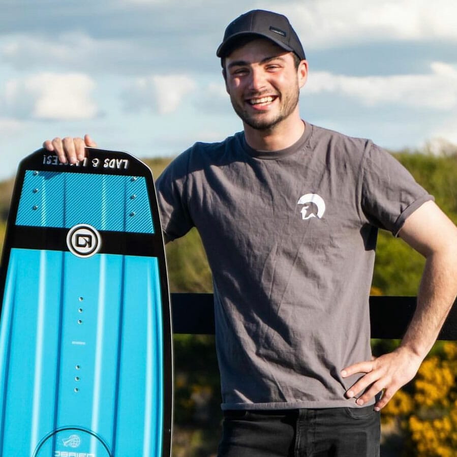 A man next to a wakeboard on a boat.