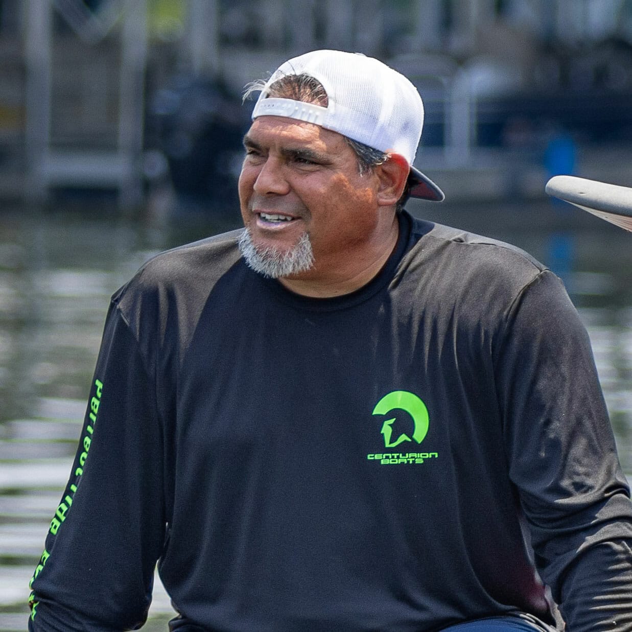 A man sitting on a canoe near a wakesurf board.