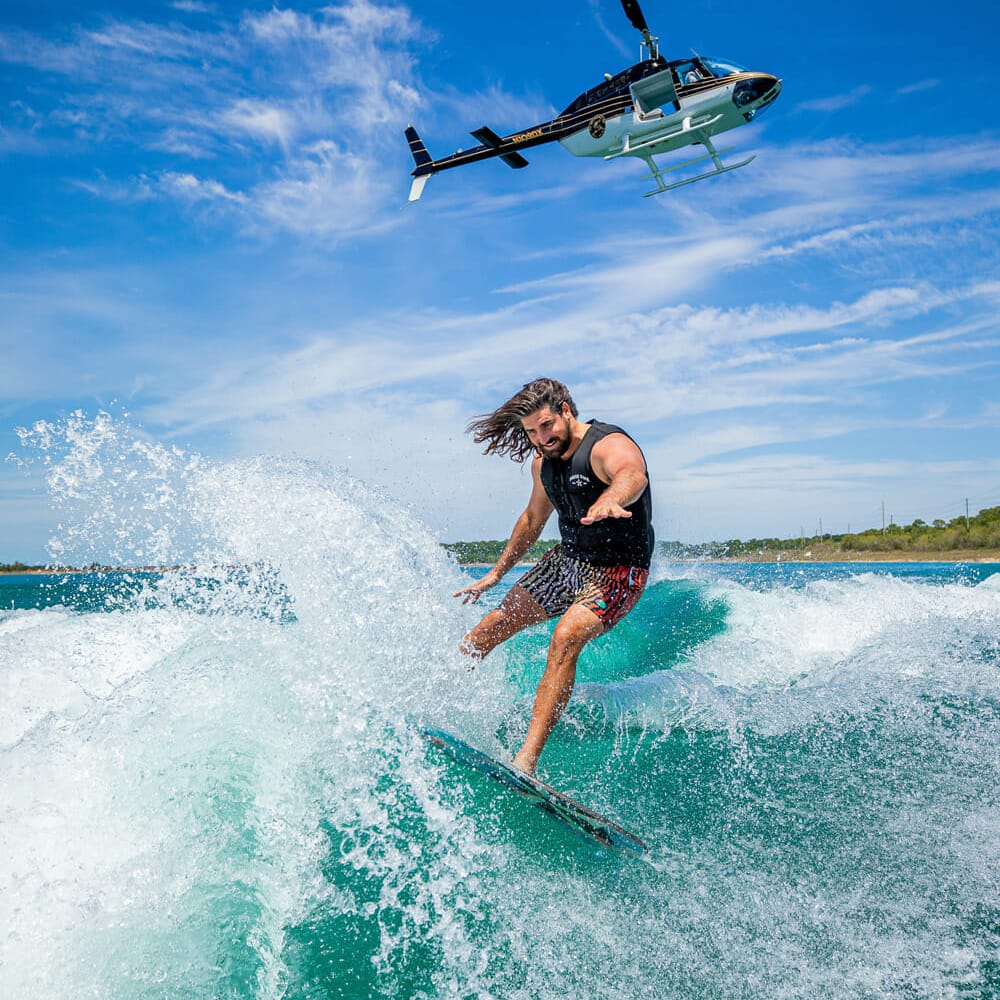 A man is wakesurfing behind a boat.