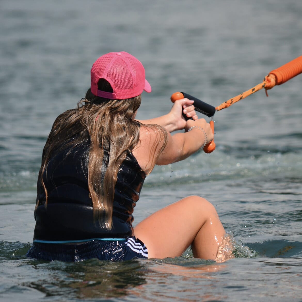 A woman is wakesurfing behind a wakeboat.