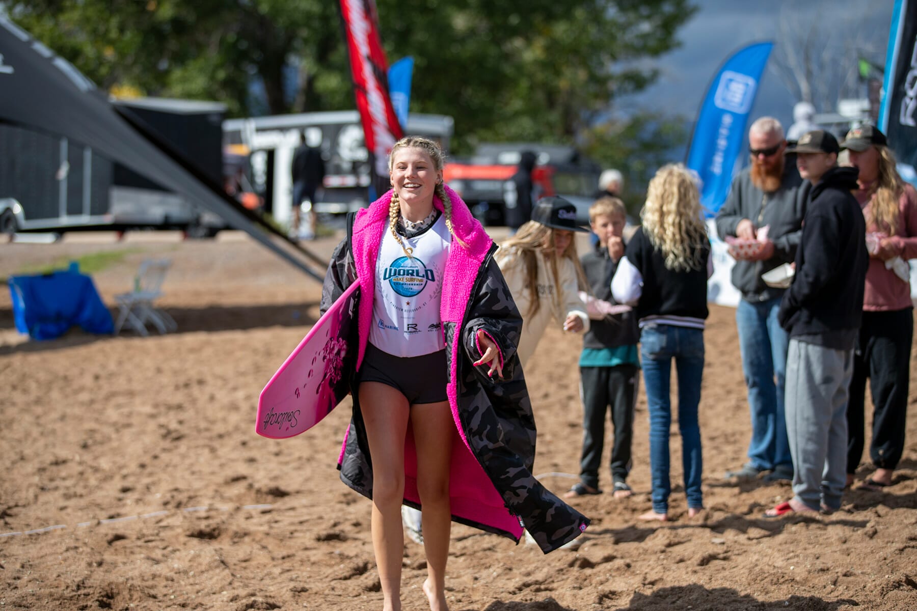 A girl in a pink hoodie walking on the sand.