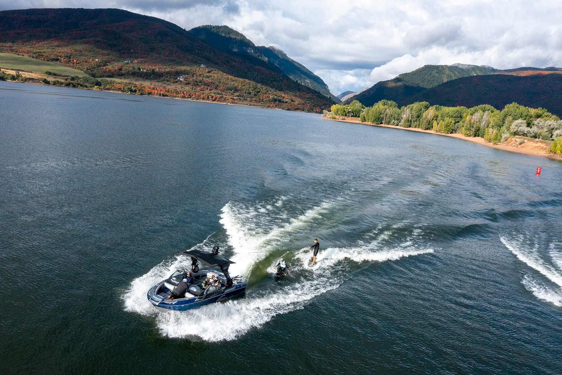 Two water skiers on a lake with mountains in the background.