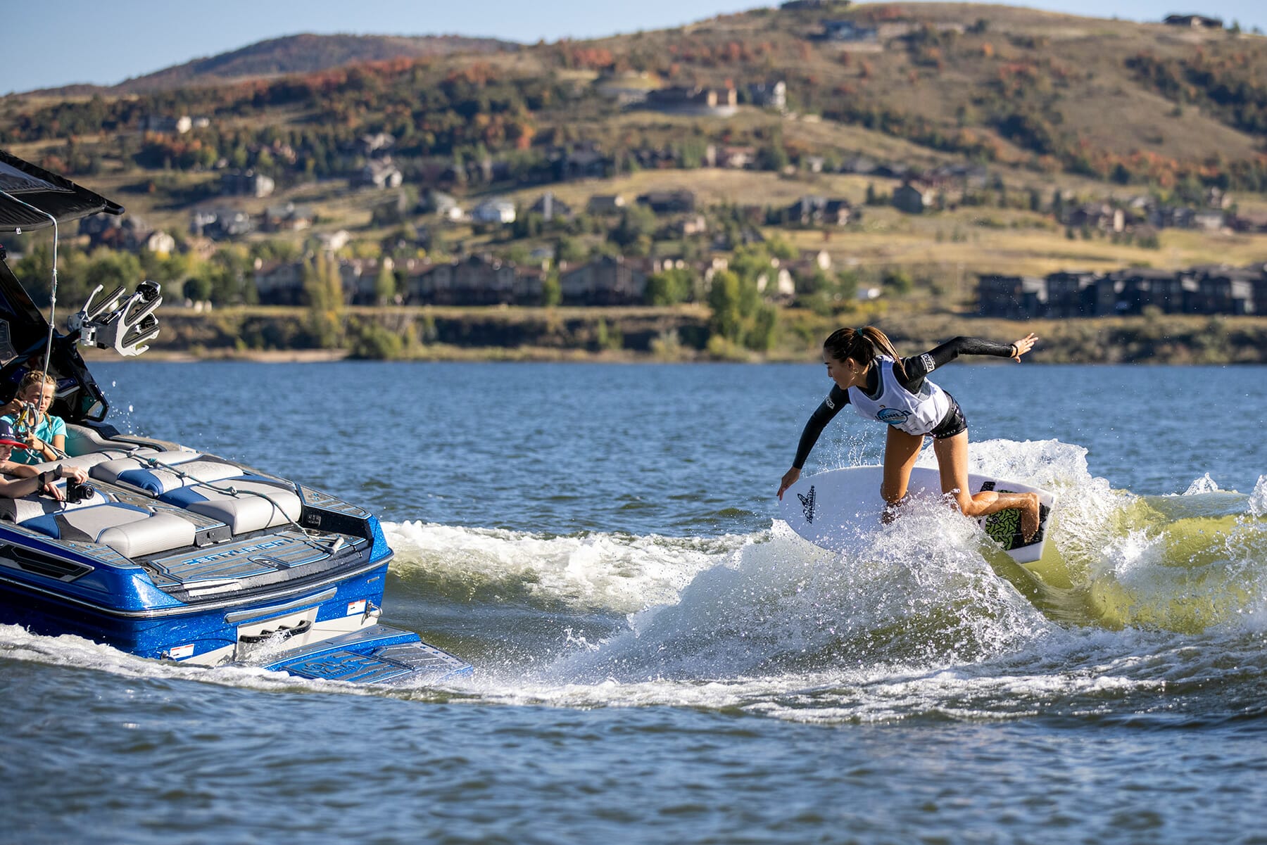 A woman is riding a surfboard in the water near a boat during the 2024 WWSC Day 2 Recap.