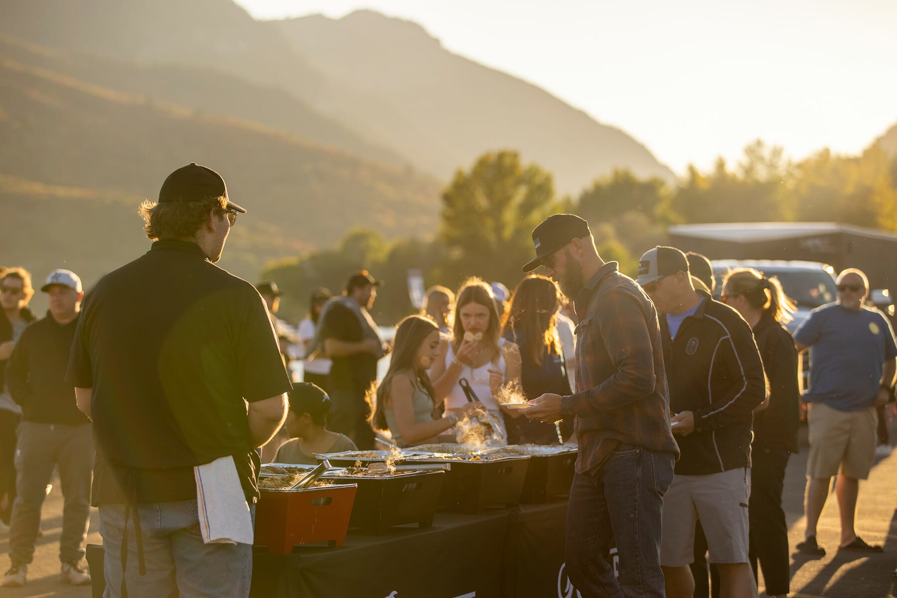 A group of people standing around a table at the 2024 WWSC Day 2 Recap outdoor event.