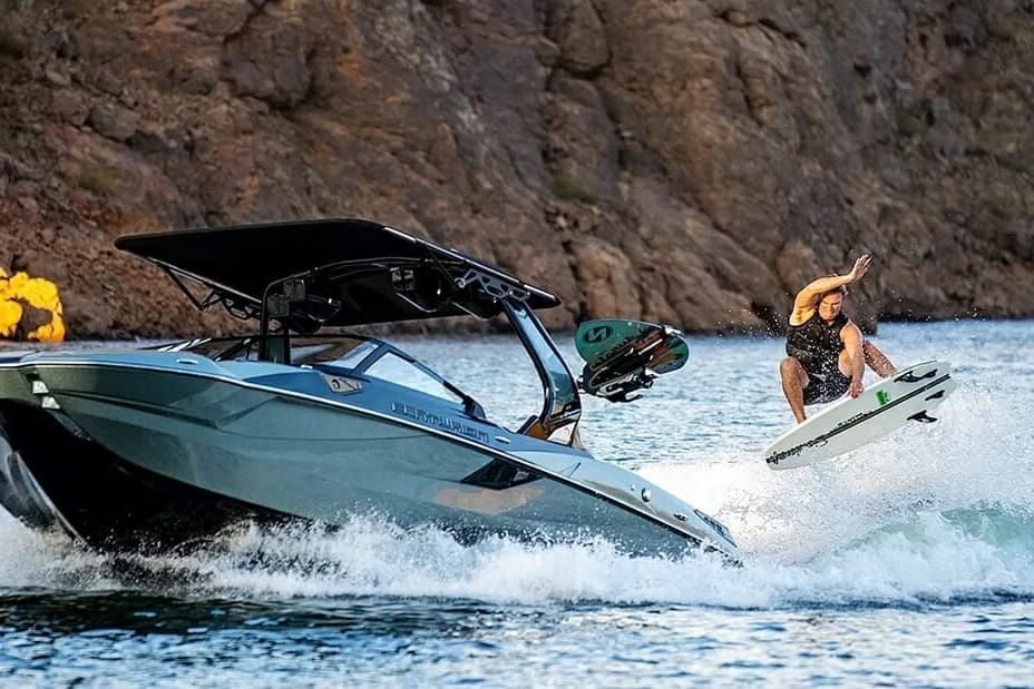 A man is riding a wakesurf board on a boat.