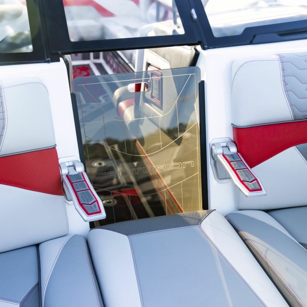 The interior of a wakeboat with a seat and a steering wheel.