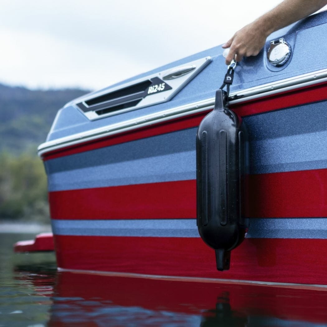 A person is holding a bag on the side of a wakeboat.