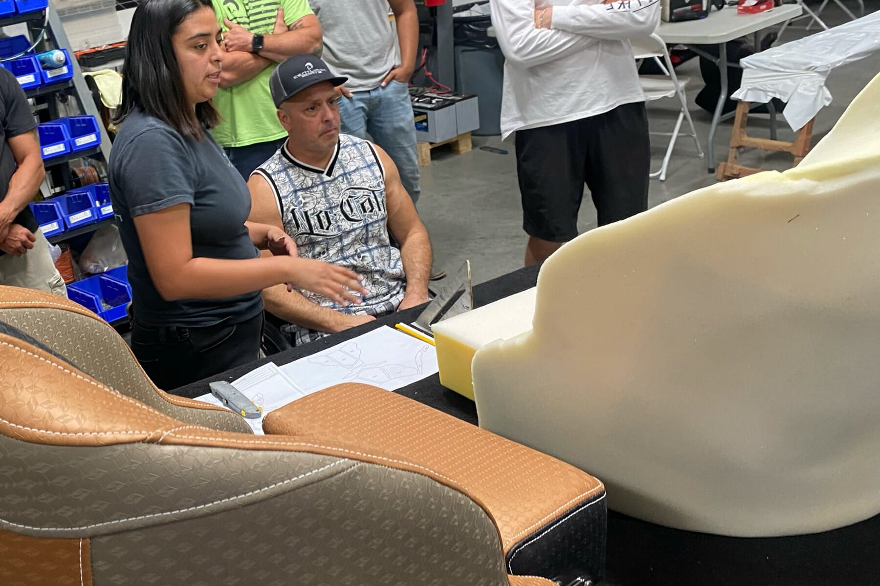 A group of people inspecting a Custom Boat Seat at a workshop.