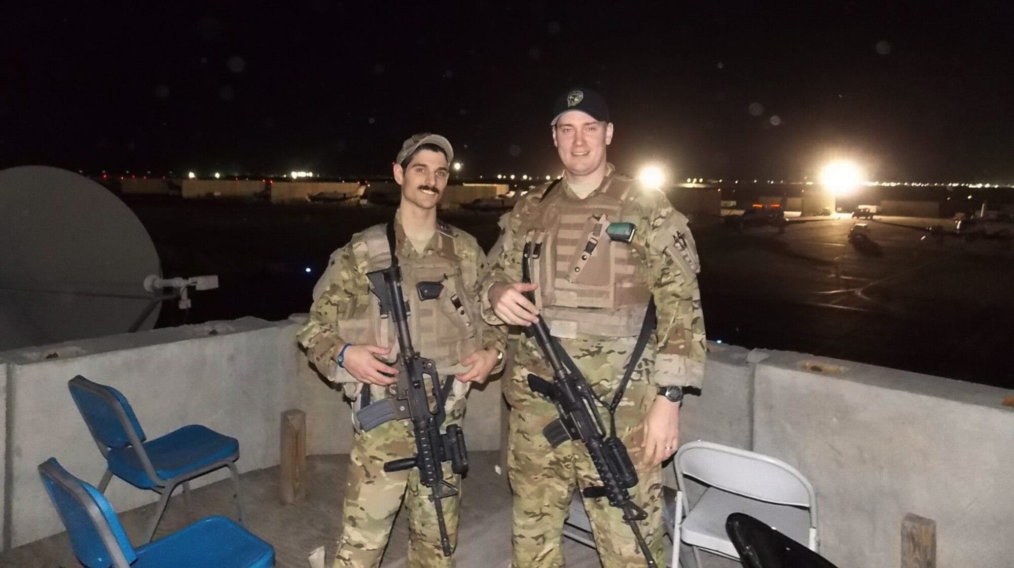 Two men in military uniforms standing next to each other at night.