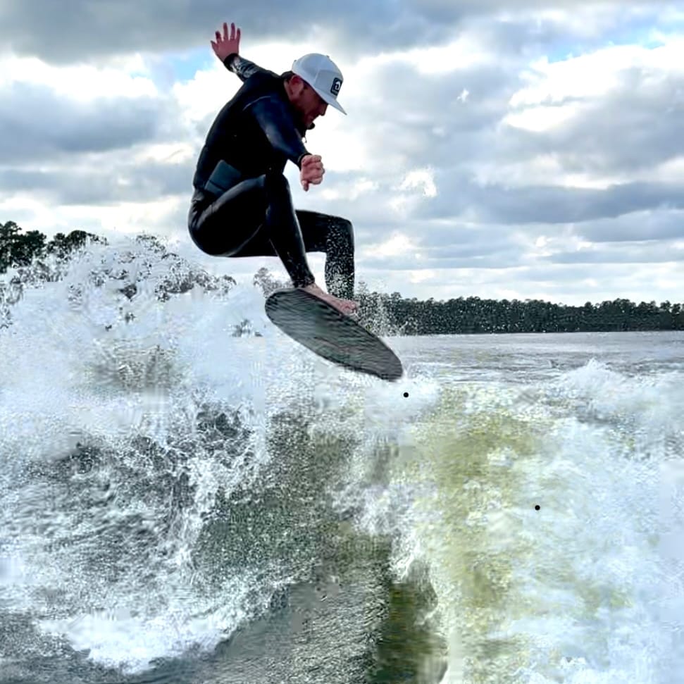 A man in a wet suit riding a wave on a surfboard.