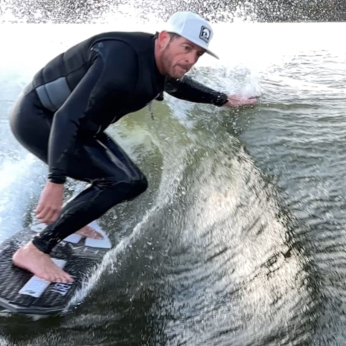 A man in a wetsuit riding a wave on a surfboard.