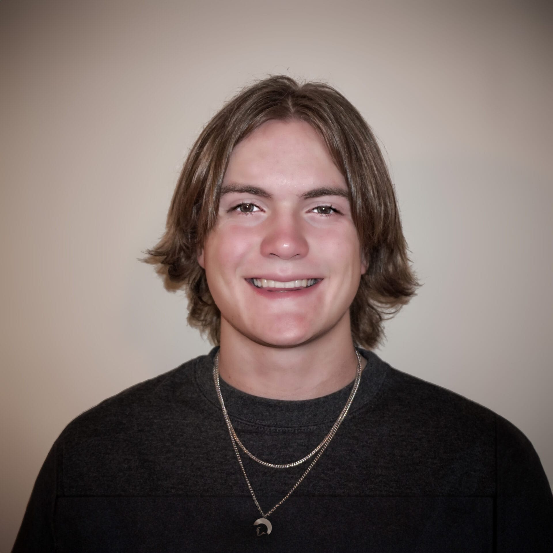 A young man with long hair and a necklace.