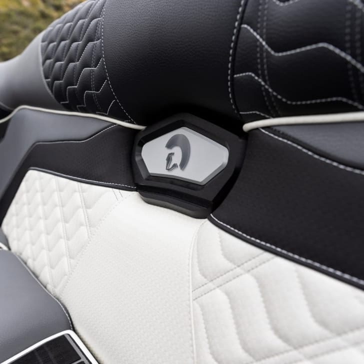 Close-up of a car seat with black and white leather upholstery featuring geometric patterns and a small, centered logo with a helmet design.