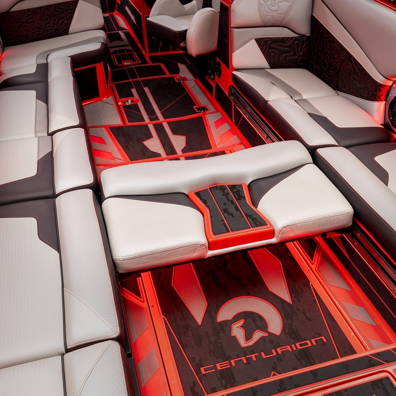 Interior of a red and white luxury boat with multiple cushioned seating areas, cup holders, and LED lighting. The floor features the 