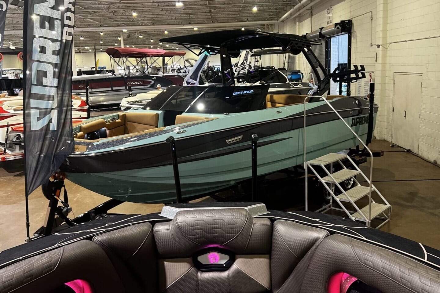 A boat showroom with various models, prominently featuring a green and black watercraft labeled 