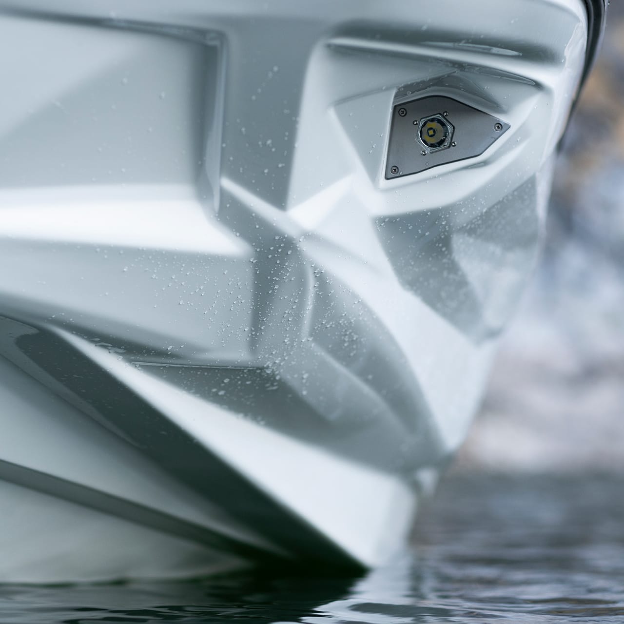 Close-up of the angular, white bow of a Centurion Fe Series boat in the water, showcasing a mounted light fixture.