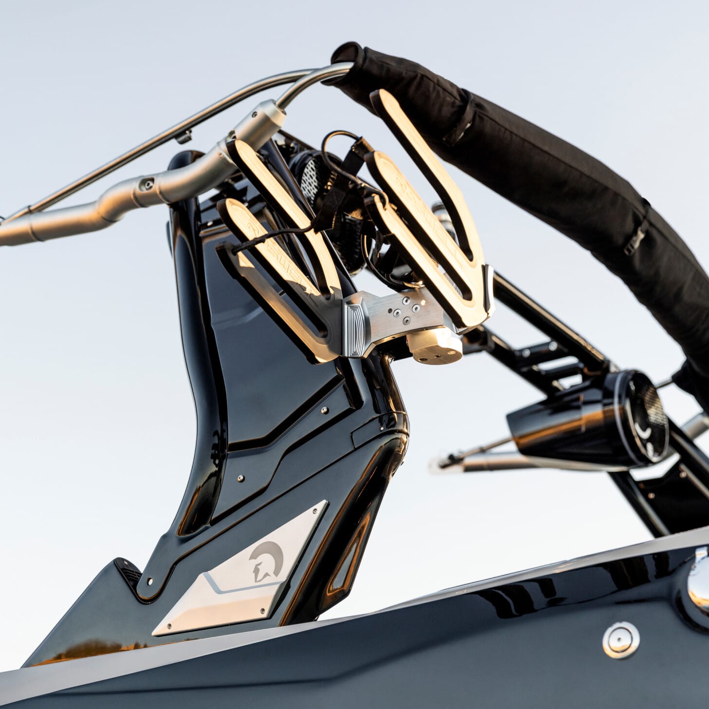 Close-up of a sleek, modern boat wakeboard tower with polished metal details and a sleek design against a clear sky.