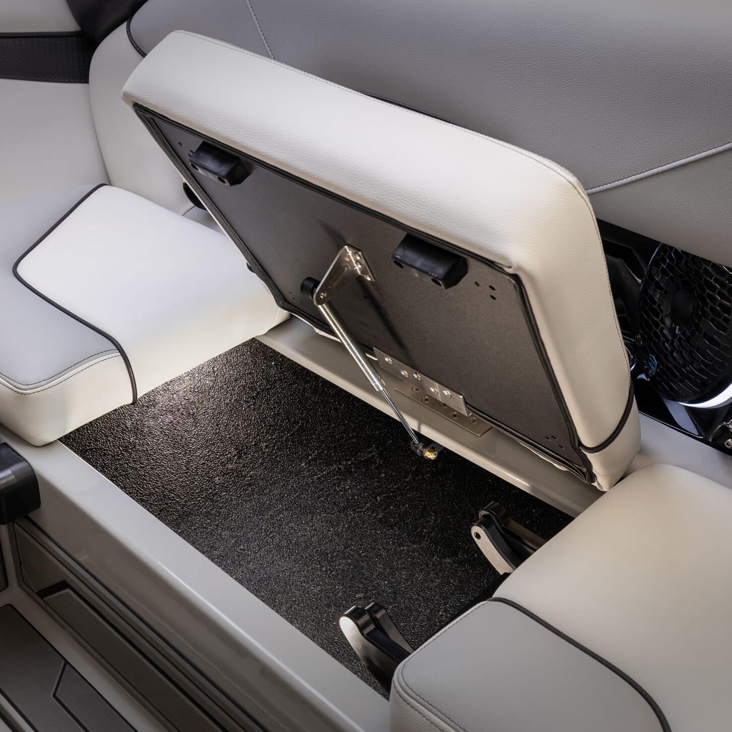 Open rear seat revealing a hidden storage compartment underneath. The seat is upholstered in light-colored material with dark accents.