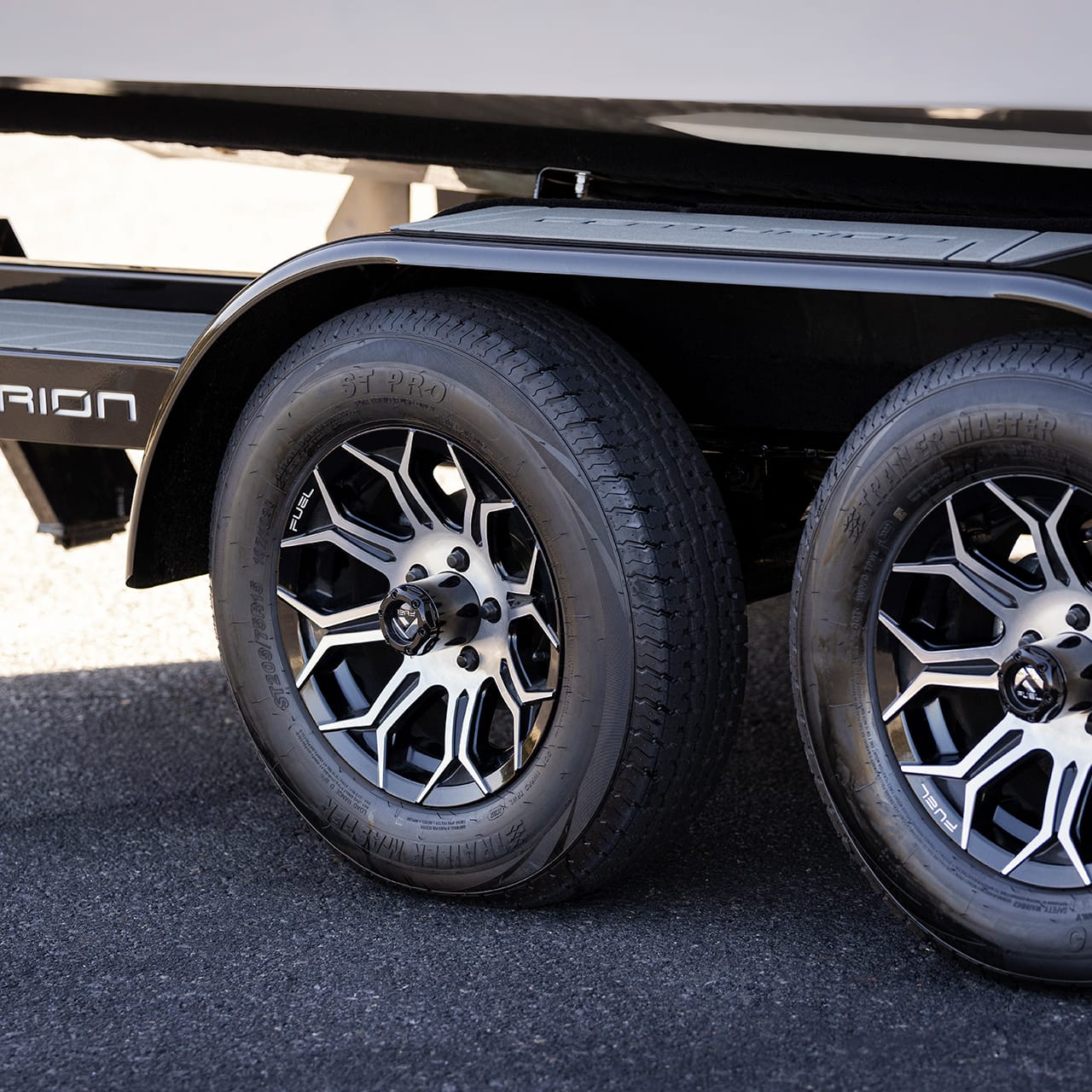 Close-up of two stylish wheels with metallic spokes on a Centurion trailer parked on a paved surface.