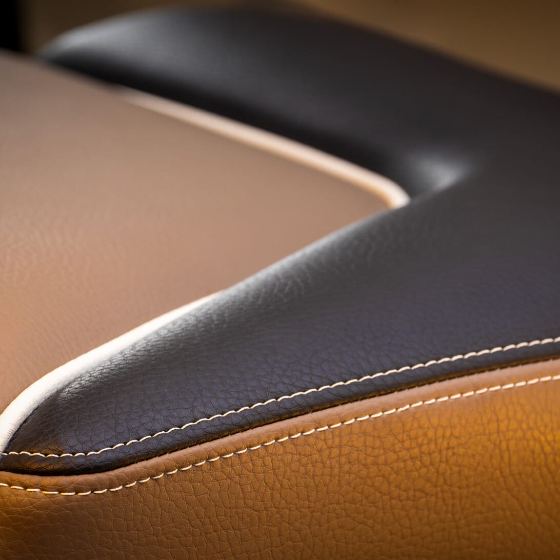 Close-up of a brown and black leather texture with white stitching detail.