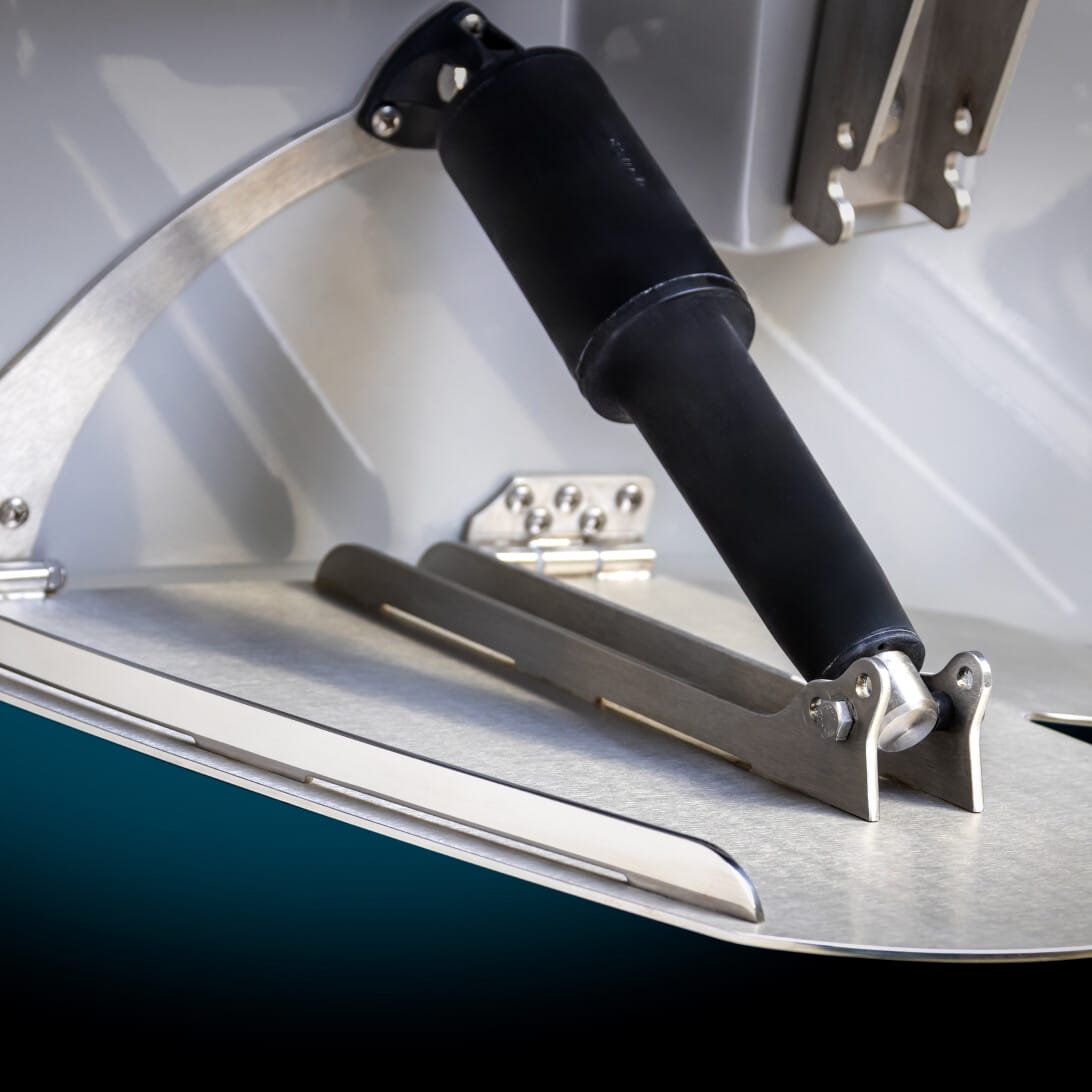 Close-up of a boat trim tab with a hydraulic actuator, mounted on a metallic surface.