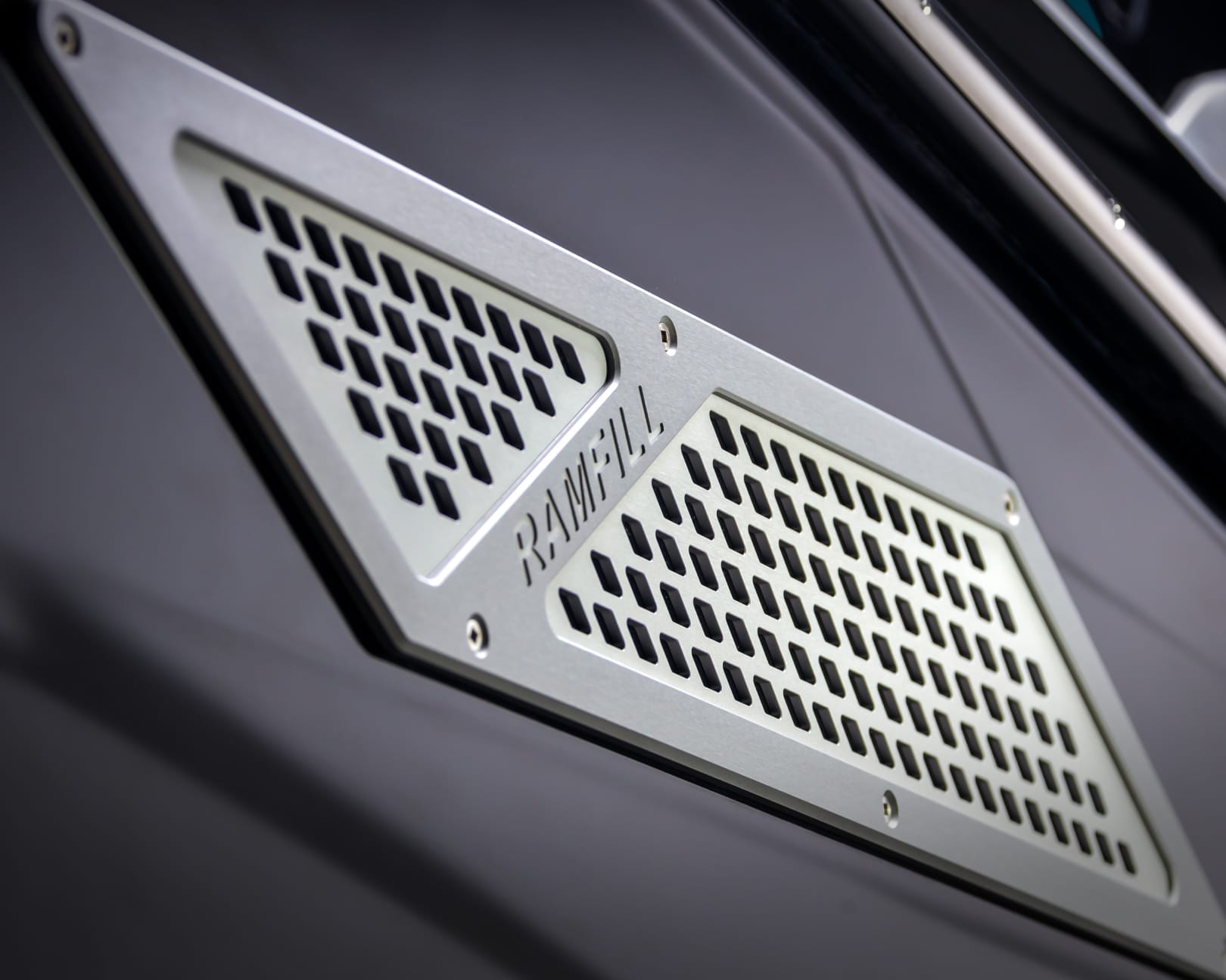 Close-up of a metallic Ramfill vent with a geometric grid pattern on a dark surface, characteristic of the Centurion Nv Series' sleek design.