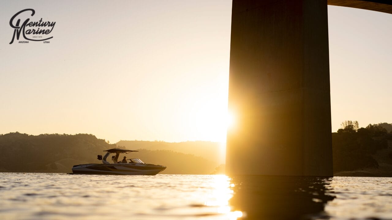 A boat cruises on a lake at sunset near a large bridge pillar, with hills in the background.