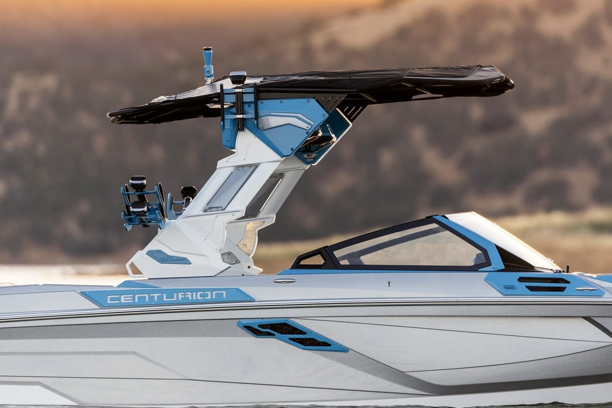 A sleek Centurion boat with a modern blue and white design, featuring a black canopy, cruising on calm water.