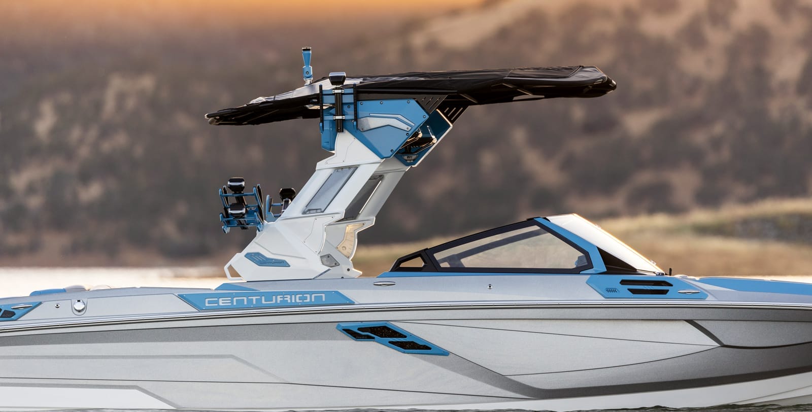 A sleek Centurion boat with a modern blue and white design, featuring a black canopy, cruising on calm water.