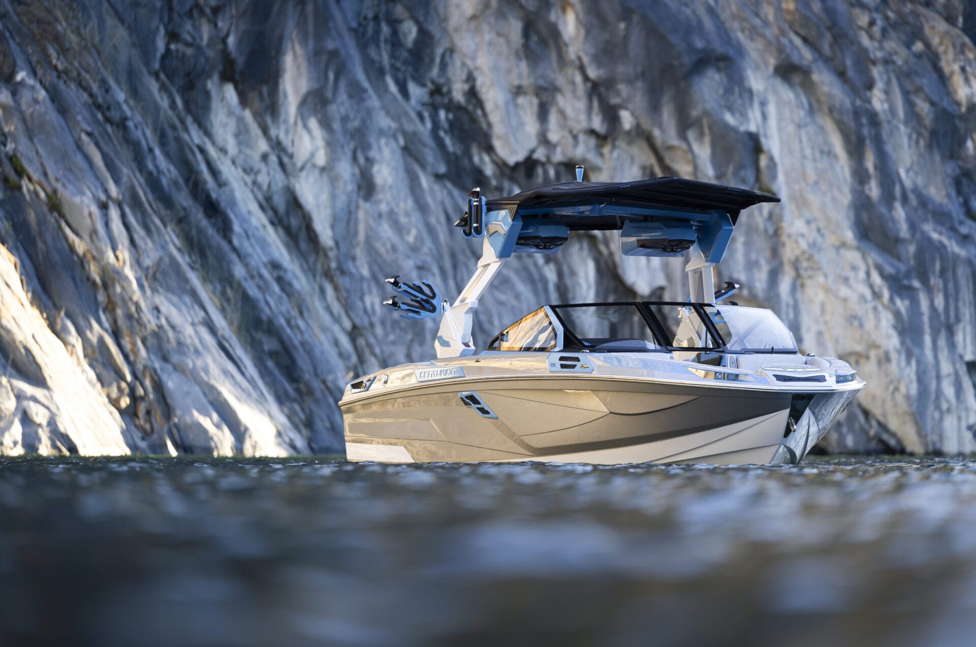 A motorboat with a canopy floats near a rock cliff in a body of water.