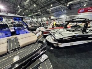 Indoor boat show featuring multiple luxury boats with various designs and seating options under bright overhead lighting.