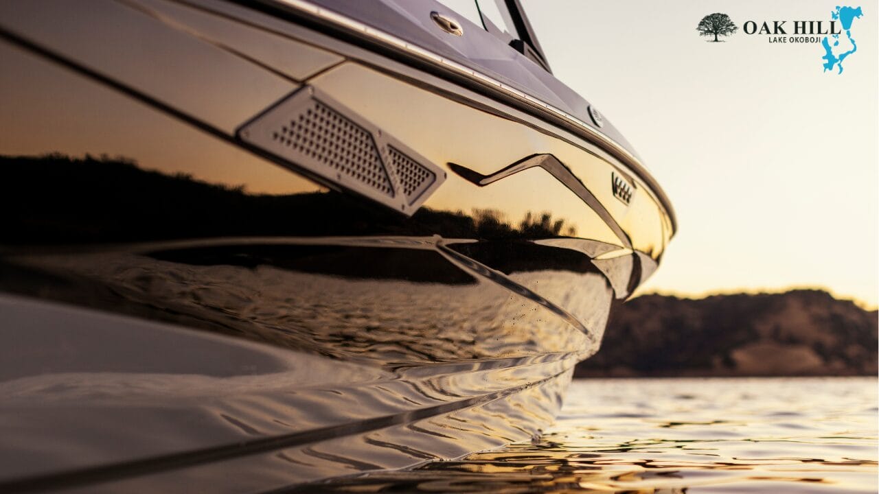 Close-up of a boat's side with reflections on the water at sunset. The Oak Hill Lake Osborn logo is in the top right corner.