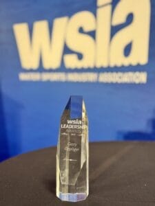 Crystal award with "WSIA Leadership Awards 2023, Gerry Oppliger" engraved on it, placed on a table. Background shows "WSIA" logo.